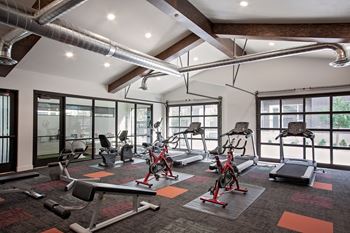 A gym with a variety of equipment including treadmills, stationary bikes, and weight benches.